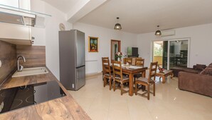 Eine moderne Küche mit Einbauherd, Kühlschrank und einer Essecke mit Holztischen und -stühlen.