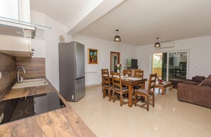 Eine moderne Küche mit Einbauherd, Kühlschrank und einer Essecke mit Holztischen und -stühlen.
