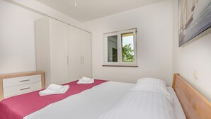 Ein Schlafzimmer mit einem Bett, einem Kleiderschrank, einem Fenster und einem Bild an der Wand.
