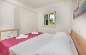 Ein Schlafzimmer mit einem Bett, einem Kleiderschrank, einem Fenster und einem Bild an der Wand.