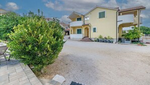 Ein zweistöckiges Haus mit Auffahrt, einem kleinen Garten und einem Balkon.