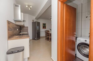 A compact kitchen with a built-in stove, a refrigerator, and a washing machine. - Apartment Villa Dijana (Vodice)