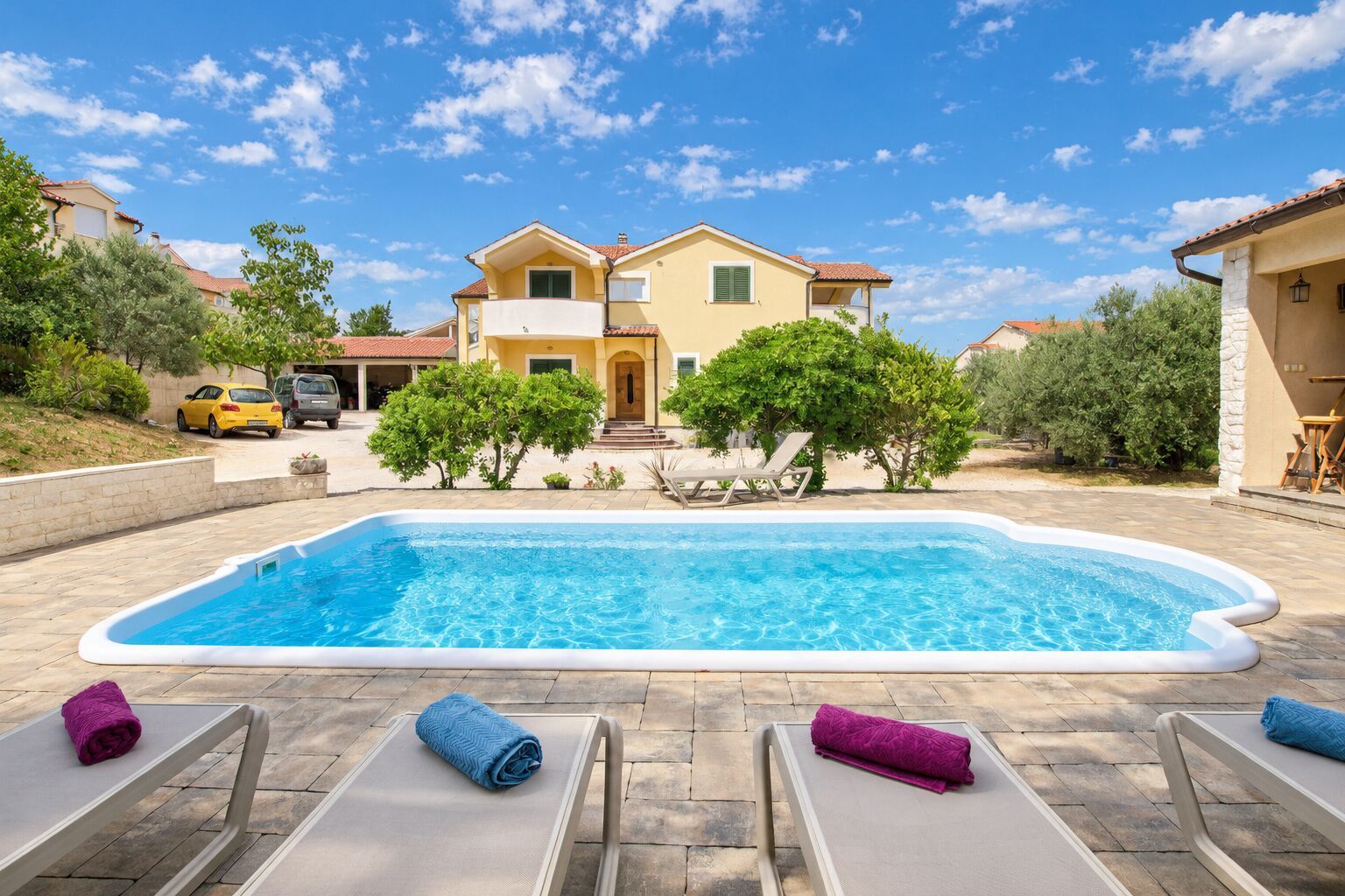 Ein Schwimmbecken mit Liegestühlen und einem Haus im Hintergrund.