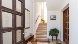 A hallway with a wooden door, a staircase, a potted plant, and a framed picture on the wall. - Apartments Jadranka sea View (Novalja)