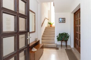 A hallway with a wooden door, a staircase, a potted plant, and a framed picture on the wall. - Apartments Jadranka sea View (Novalja)