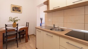 A compact kitchen with a dining area, a sink, and cabinets. - Apartments Jadranka sea View (Novalja)