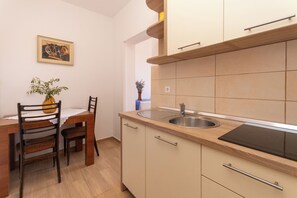 A compact kitchen with a dining area, a sink, and cabinets. - Apartments Jadranka sea View (Novalja)