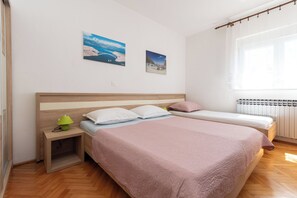 A bedroom with two beds, a nightstand, a lamp, and two wall-mounted pictures. - Apartments Jadranka sea View (Novalja)