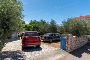 A stone wall, parked cars, and a stone pathway. - Apartments Jadranka sea View (Novalja)