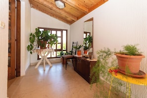 A room with a wooden ceiling, a chair, a desk, and several potted plants. - Apartments Jadranka sea View (Novalja)