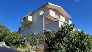 Um edifício residencial com várias andares, sacadas, antena parabólica e vegetação ao redor.