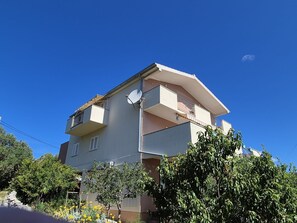 A multi-story residential building with balconies, satellite dish, and surrounding greenery. - Apartments Stipan (Marina)