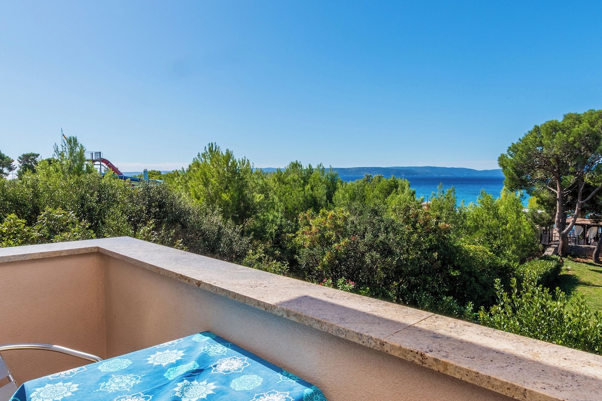A balcony with a table and chairs, overlooking a pool and a clear blue sky.