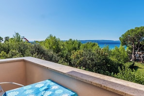 A balcony with a table and chairs, overlooking a pool and a clear blue sky. - Apartments Molly (Punat)