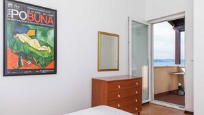 Ein Schlafzimmer mit einem Bett, einer Holzkommode, einem Spiegel und einem Bild an der Wand.
