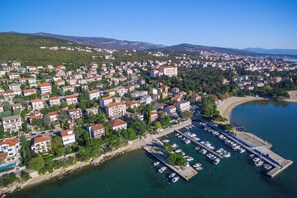 An aerial view of a coastal town with residential buildings, a marina, and a beach. - House Holiday House Art (Crikvenica)