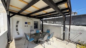 A covered patio with a table and chairs, a door, and a view of a snowy landscape. - House Holiday House Art (Crikvenica)