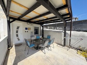 A covered patio with a table and chairs, a door, and a view of a snowy landscape. - House Holiday House Art (Crikvenica)