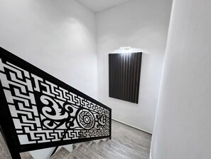 A hallway with a decorative black and white geometric pattern, a wall-mounted light fixture, and a vertical black panel. - House Holiday House Art (Crikvenica)