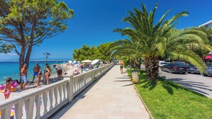 A coastal promenade with a clear view of the sea, palm trees, and a sidewalk lined with beachgoers. - House Holiday House Art (Crikvenica)