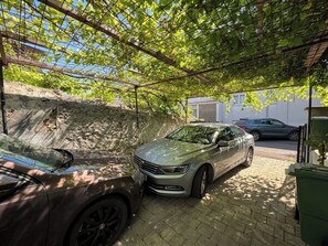 A car parked under a pergola with a brick wall and a building in the background. - House Holiday House Art (Crikvenica)