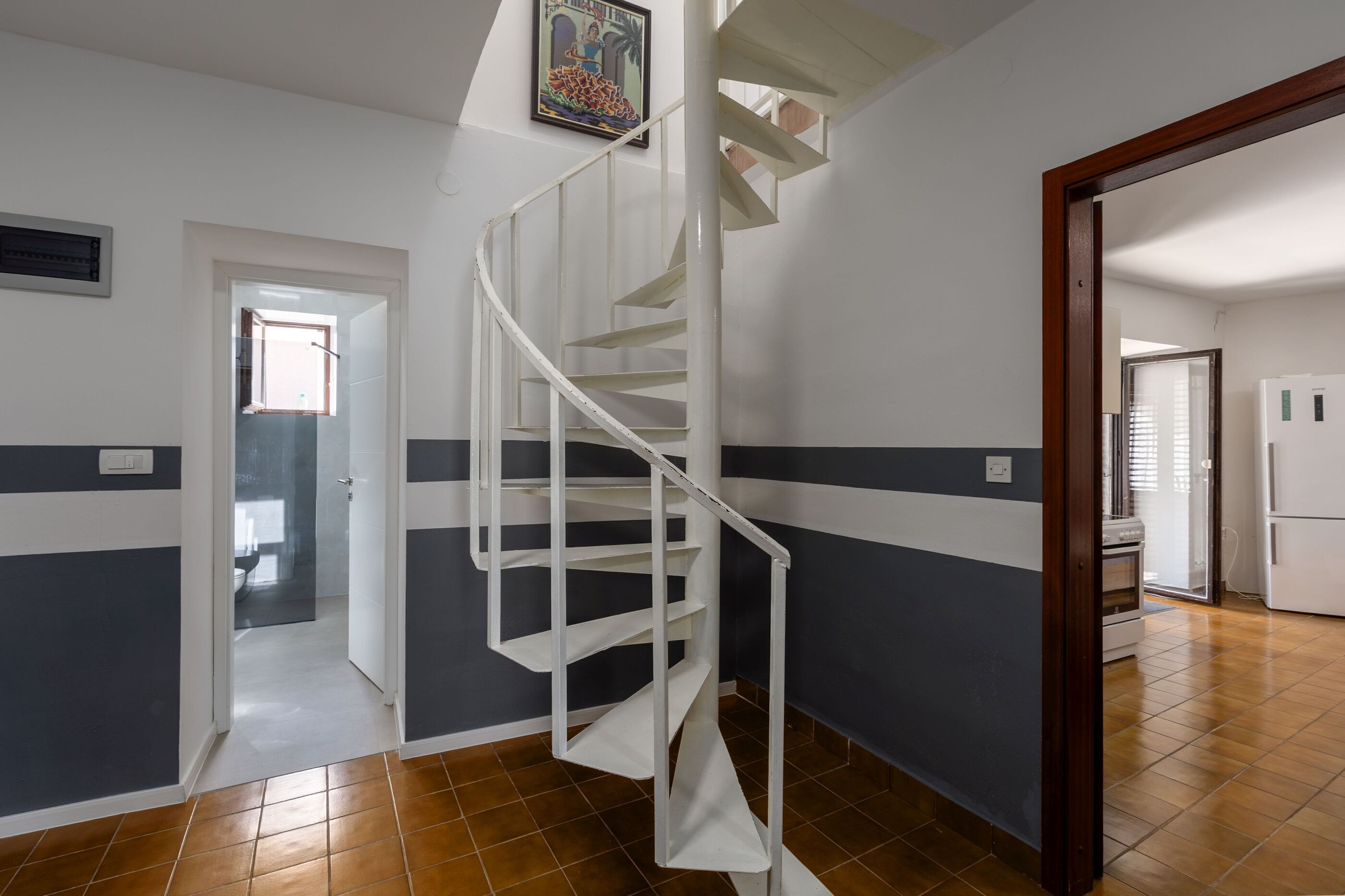 A spiral staircase in a hallway with a door leading to another room.