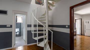 A spiral staircase in a hallway with a door leading to another room.