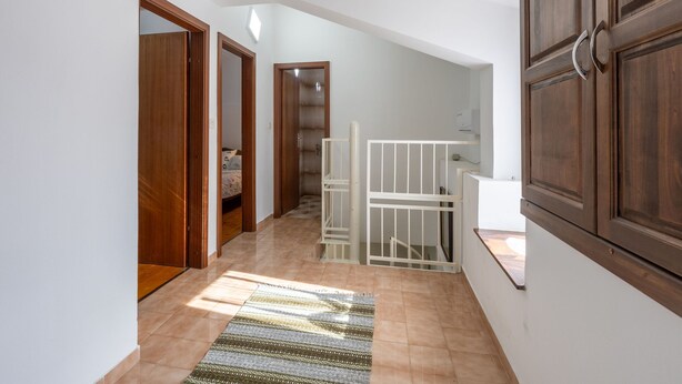 A hallway with a wooden door, a white gate, and a staircase leading to an upper level. - House Bakic (Marcana)