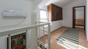 A room with a white air conditioner, a wooden cabinet, a striped rug, and a white railing. - House Bakic (Marcana)