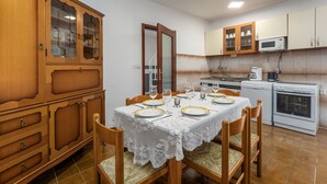 A dining area with a table set for four, wooden cabinets, a microwave, and a stove. - House Bakic (Marcana)
