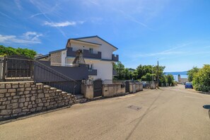 A two-story residential building with a stone staircase, a gated entrance, and a view of the sea in the background. - Apartment Evelin (Crikvenica)