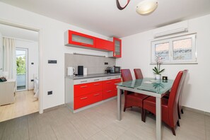 A modern kitchen with red cabinets, a glass dining table, and red chairs. - Apartment Evelin (Crikvenica)