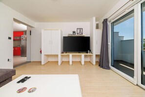 A modern living room with a flat-screen TV, a white sofa, and a dining table. - Apartment Evelin (Crikvenica)