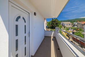 A balcony with a white door, a clear view of the neighborhood, and a metal railing. - Apartment Evelin (Crikvenica)