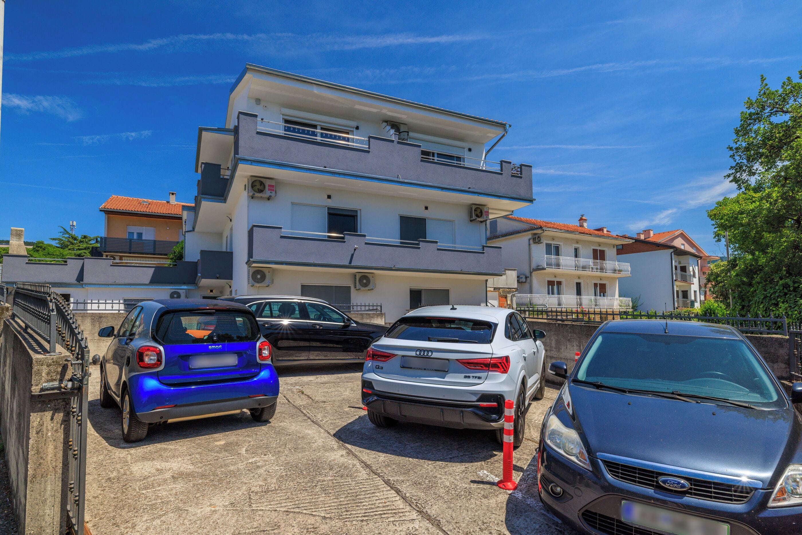 Un edificio residencial de varios pisos con una zona de estacionamiento.