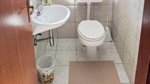 Ein kleines Badezimmer mit Toilette, Waschbecken und einem Fenster über der Toilette.