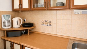Eine Küche mit Holzausstattung, einer Kaffeemaschine, einem Wasserkocher und einer gefliesten Spritzschutzwand.