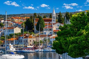 A coastal town with a marina, buildings with red-tiled roofs, and a prominent church steeple. - Apartment Luna (Rogoznica)