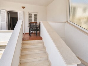 A staircase with a handrail, a dining table with chairs, and a window with blinds. - Apartment Luna (Rogoznica)