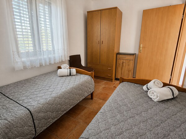 A room with two beds, a wooden wardrobe, a small cabinet, and a chair. - Apartment Luna (Rogoznica)