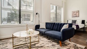 Een moderne woonkamer met een donkerblauwe bank, een ronde salontafel en een vloerkleed met een patroon.