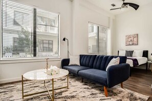 Ein modernes Wohnzimmer mit einem dunkelblauen Sofa, einem runden Couchtisch und einem gemusterten Teppich.