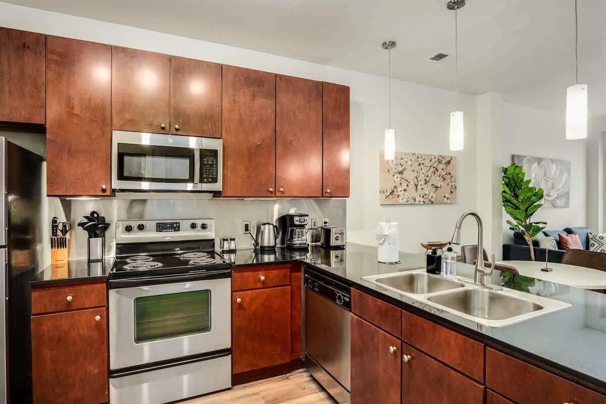 A modern kitchen with stainless steel appliances, wooden cabinets, and a double sink.