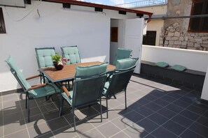 Eine Terrasse mit Tisch und Stühlen, einem Blumentopf und einer Steinmauer im Hintergrund.