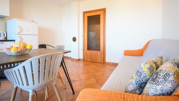 A dining area with a table, chairs, a refrigerator, and a door. - Apartment Ines (Novi Vinodolski)