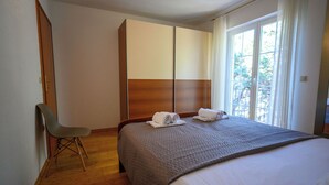 A hotel room with a bed, a chair, a wardrobe, and a window with a view. - Apartment Ines (Novi Vinodolski)