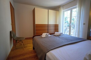 A hotel room with a bed, a chair, a wardrobe, and a window with a view. - Apartment Ines (Novi Vinodolski)
