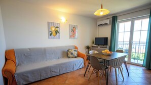 A living room with a sofa, dining table, chairs, a TV, and artwork on the walls. - Apartment Ines (Novi Vinodolski)