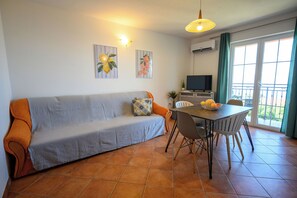 A living room with a sofa, dining table, chairs, a TV, and artwork on the walls. - Apartment Ines (Novi Vinodolski)