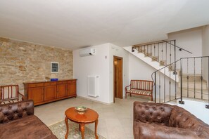 Ein Wohnzimmer mit Steinswand, Holzschrank, Sofa, Couchtisch und Treppe.